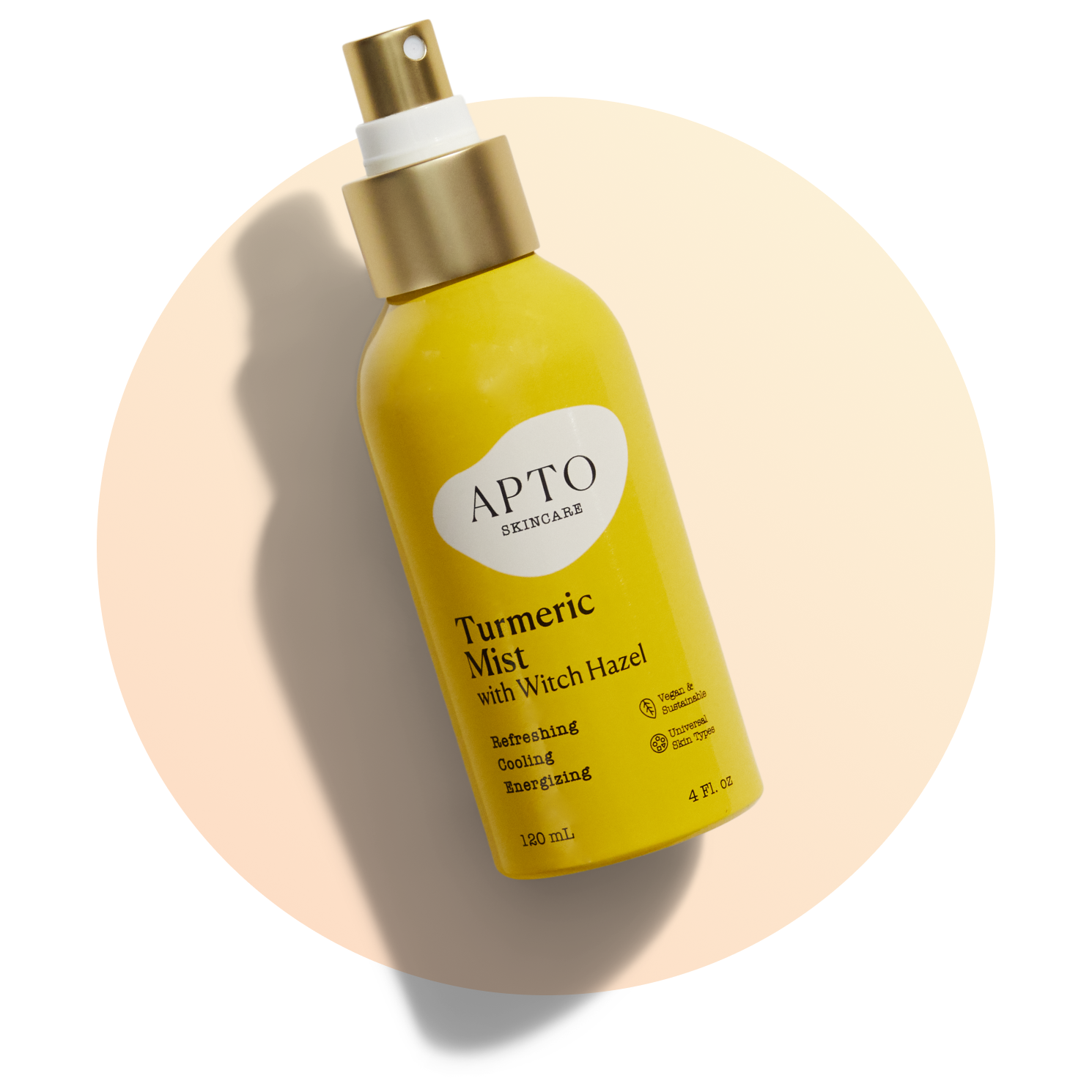 A yellow spray bottle labeled APTO Skincare Turmeric Mist with Witch Hazel stands upright on a light background, casting a soft shadow. The bottle has a gold cap and contains 120 ml (4 fl. oz.).
