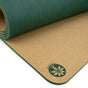 A close-up of a rolled-out Pond of Harmony Aura Cork Yoga Mat by Yoloha Yoga shows its cushioned surface and green edges. A leaf and lotus logo with “Yoloha Yoga” is printed on the bottom corner, highlighting its appeal as a sustainable yoga mat.