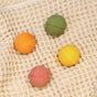 Four vibrant bath bombs from the Pacha Soap Co. Bath Bomb Set – Autumn Heirlooms Collection—green, yellow, orange, and pink—rest on a beige, textured towel. These vegan bath bombs are round and evenly arranged across the soft waffle-patterned fabric, inviting a soothing soak with their gentle fall-inspired scents.