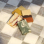 Five rectangular bars from the Pacha Soap Co. Bar Soap Set - Autumn Heirlooms Collection—with vegan, cold-processed soaps featuring various marbled and layered patterns—are arranged on a checkered marble-tiled surface in natural light.