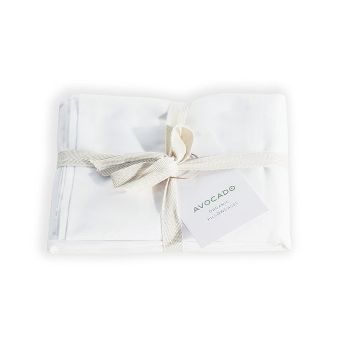 A set of white Avocado Organic Indian Cotton 400 TC Pillow Cases, neatly folded with a cream ribbon and tag—crafted from GOTS certified organic cotton with a soft sateen finish.