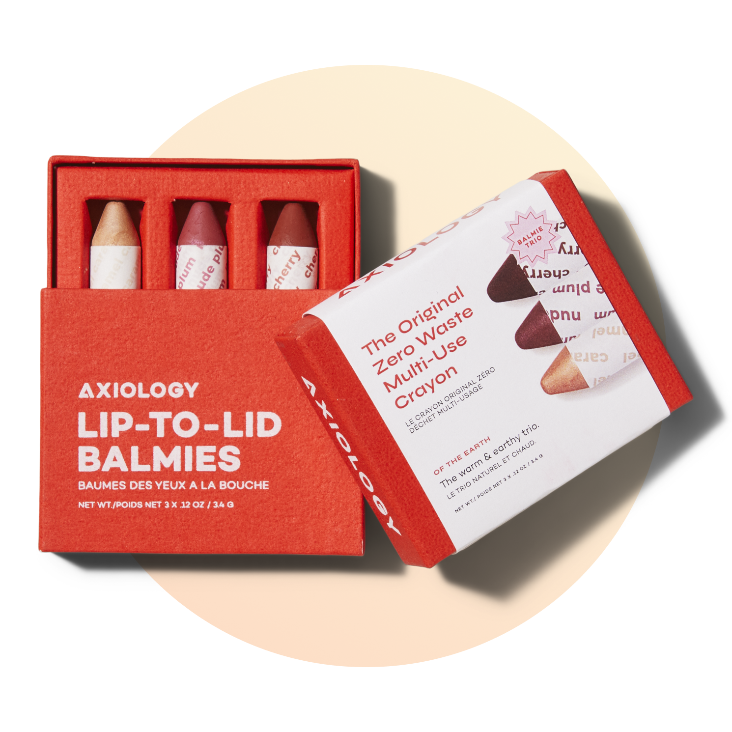 A red box labeled Axiology Lip-to-Lid Balmies contains three crayon-shaped makeup sticks, with the box partially open. Another box shows product details and images of the crayons on a light beige background.