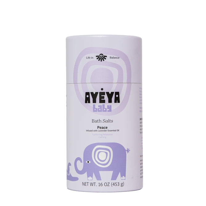 A cylindrical Ayeya Baby Bath Salts container features lavender packaging with a purple elephant and circles. The “Peace” scent, with lavender essential oil, soothes and hydrates baby’s skin. Net weight: 16 oz (453 g).