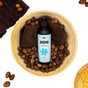 A bottle of Ayeya Moisturizing Body Wash rests in a wooden bowl with brown cloth and shea nuts, surrounded by decorative items on a white background. Its calming scent is infused with soothing essential oils.