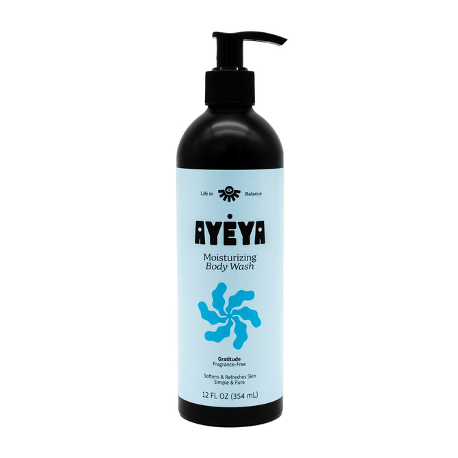 A black Ayeya Moisturizing Body Wash bottle with a pump sits on a light blue background, featuring a blue swirl and highlighting its fragrance-free, essential oils formula for soft, hydrated skin.