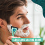 A man shaves his face with a razor and shaving cream as green text reads “Close, long-lasting shave.” The background is softly blurred with green graphic accents around the edges. He uses Preserve Shave 5 Replacement Blades (fits Preserve Shave 5 and POPi Shave 5), highlighting the effectiveness and sustainability of these eco-friendly blades from Preserve.