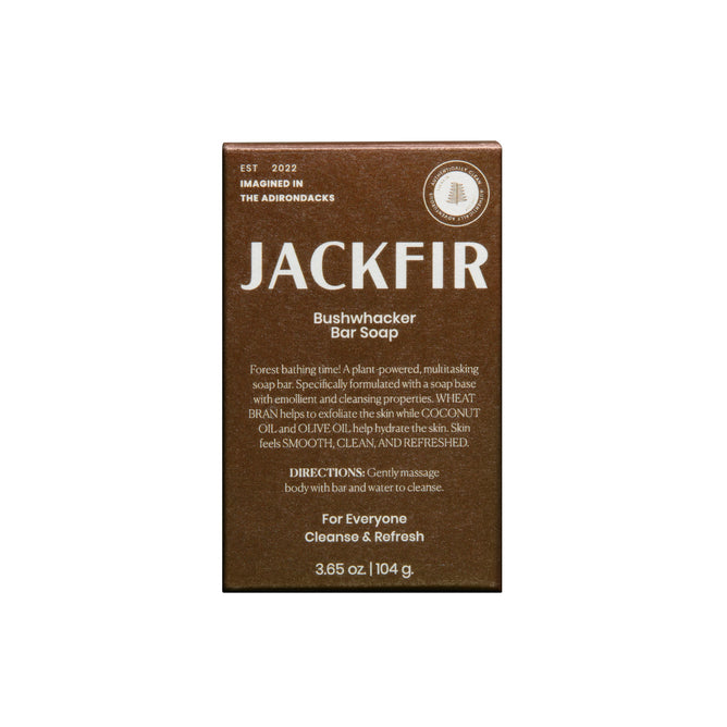 A brown rectangular box of Jackfir The Bushwhacker Bar Soap with all-natural ingredients and directions. Packaging highlights exfoliating benefits and suitability for all. Net weight: 3.65 oz (104 g).