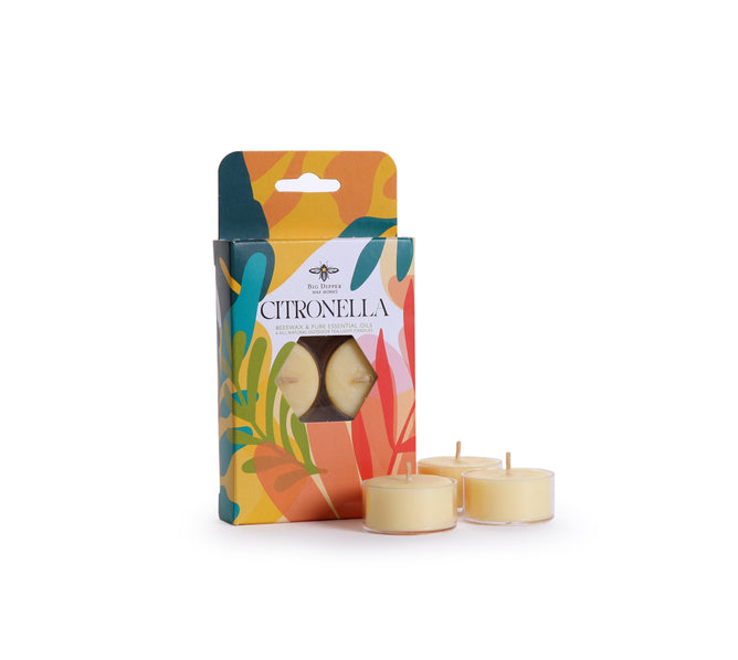 A vibrant box labeled "Big Dipper Wax Works Citronella Tea Light Candles" with a window displays the citronella tea lights inside. Three yellow tea light candles, perfect as an all-natural bug repellent and ideal for use as outdoor candles, are arranged outside the box on a white background.