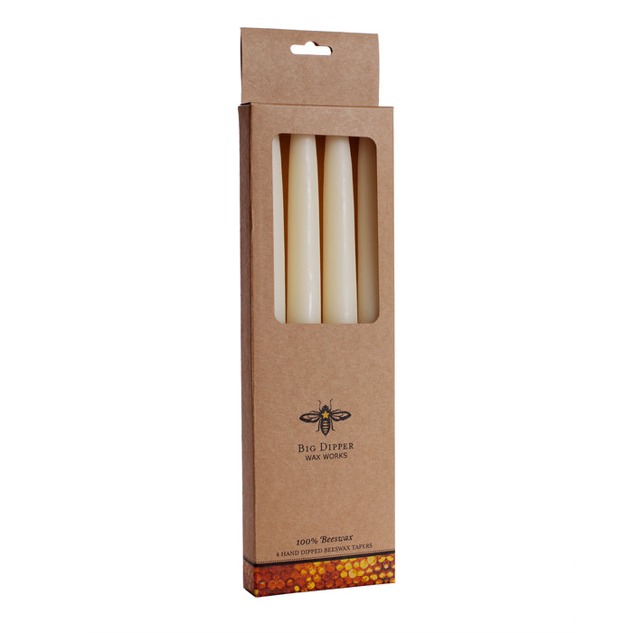 A brown box with a window displays four cream-colored beeswax tapers. Labeled Big Dipper Wax Works and Hand Dipped Tapers 4 pk, the packaging highlights pure, toxin-free candles made from 100% beeswax with a bee logo.