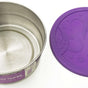 The EcoLunchBox Seal Cup Jumbo, a stainless steel container with a decorative purple silicone embossed lid, sits on a white surface. This leak-proof lunch container combines style and practicality.