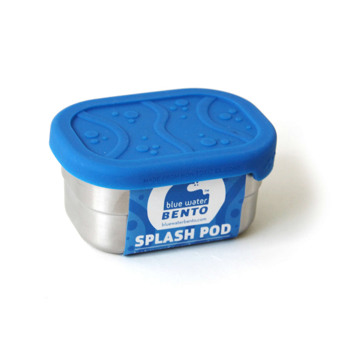 The EcoLunchBox Splash Pod is a small stainless steel lunchbox with a vibrant blue silicone lid featuring wave and dot patterns—perfect for eco-friendly, plastic-free snacking.