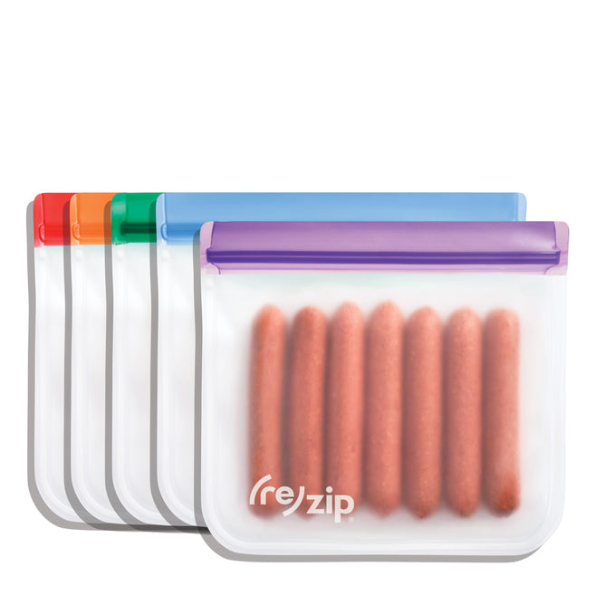 Five (re)zip Reusable Sandwich & Lunch Bags with colored zippers are displayed in a row on a white background. The front leakproof bag, featuring the (re)zip logo, holds six sausages as an eco-friendly food storage solution.