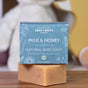 A bar of Chagrin Valley Soap & Salve's Natural Baby Soap with blue packaging and organic ingredients rests on a surface, while a plush toy is blurred in the background.