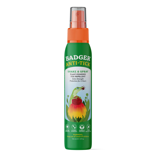 A green spray bottle labeled Badger Balm Anti-Tick Repellent Shake & Spray, featuring an illustration of a badger and a flower. The label highlights its organic, plant-powered formula for extra-strength tick protection lasting up to 8 hours, and proudly states that it is DEET-free.