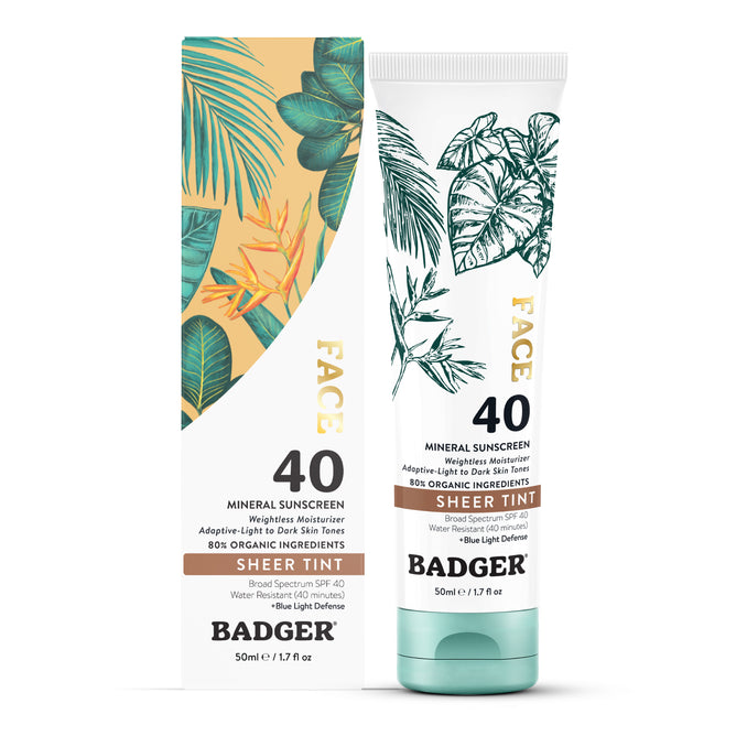 Badger Balm Tinted Face Mineral Sunscreen, SPF 40 - Sheer Tint, comes in a 50ml box and tube featuring botanical illustrations. This reef-safe zinc oxide sunscreen offers broad spectrum UVA/UVB and blue light protection with a sheer tint suitable for all skin tones.