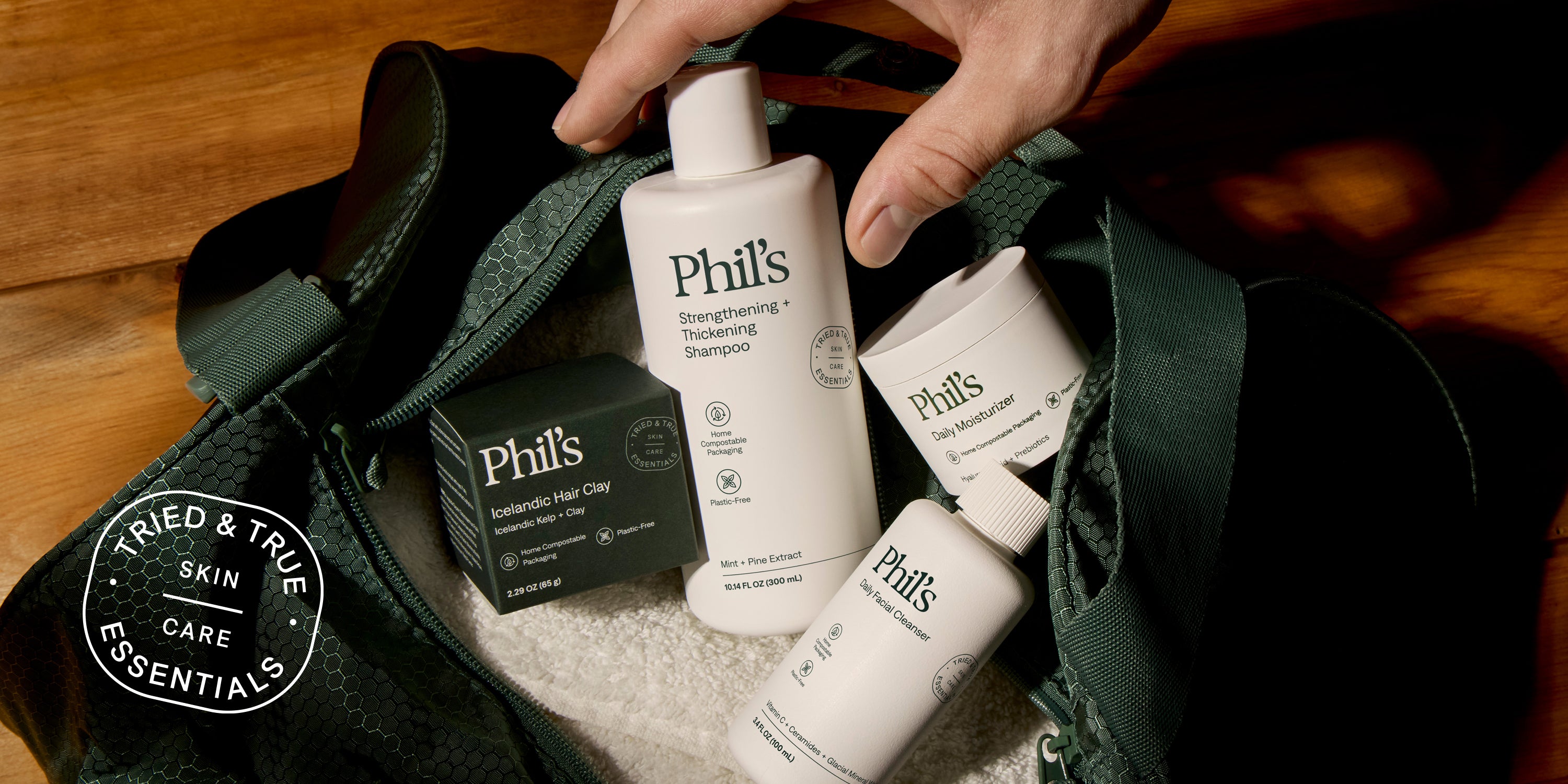 A collage of Phil’s skincare products, including a facial cleanser bottle, moisturizing cream jars, a bar of soap with foam, a tube of cream, and two round soap bars, all arranged with natural elements like leaves and water droplets.