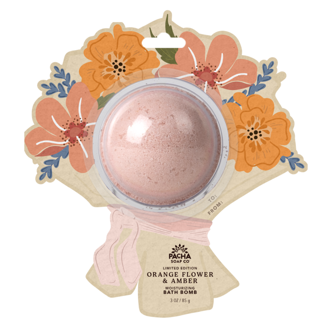 A round pink floral bath bomb from Pacha Soap Co. comes in a flower-shaped package with orange and pink blooms. The label reads “Bath Bomb Card - Orange Flower & Amber.”.