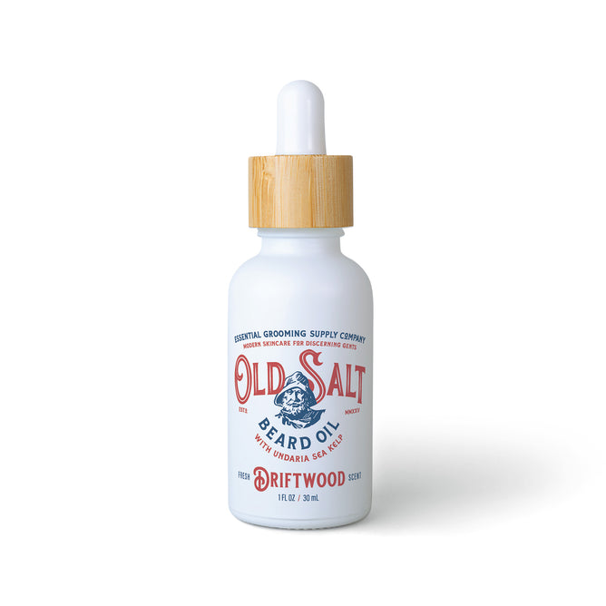 A white glass dropper bottle labeled Old Salt Beard Oil (Sea Kelp) with a wooden cap and blue and red text, designed for beard care, containing 1 fl oz (30 ml) of product.