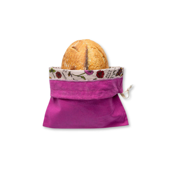 A round loaf of bread sits partially inside the Bee's Wrap Artisan Bread Bag, featuring a floral-patterned trim for reusable bread storage, displayed against a white background.