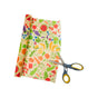 A pair of scissors cutting a colorful Bee's Wrap Beeswax Wraps for Food - Cut to Size Roll with fruit and vegetable illustrations, ideal for customizable kitchen rolls or sandwich wraps, shown on a white background.