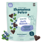 A bag of Shameless Pets Blueberried Treasure Soft-Baked Dog Treats shows treat pieces, blueberries, mint leaves, and a cartoon dog holding a spoon. The grain-free packaging notes these antioxidant treats are made in the USA.