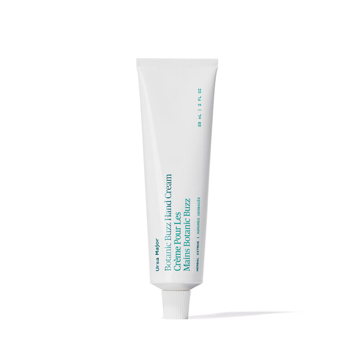A white tube of Ursa Major Botanic Buzz Hand Cream stands upright on a plain white background, its teal and black label reflecting nourishing ingredients like Bergamot to help rehydrate your hands.