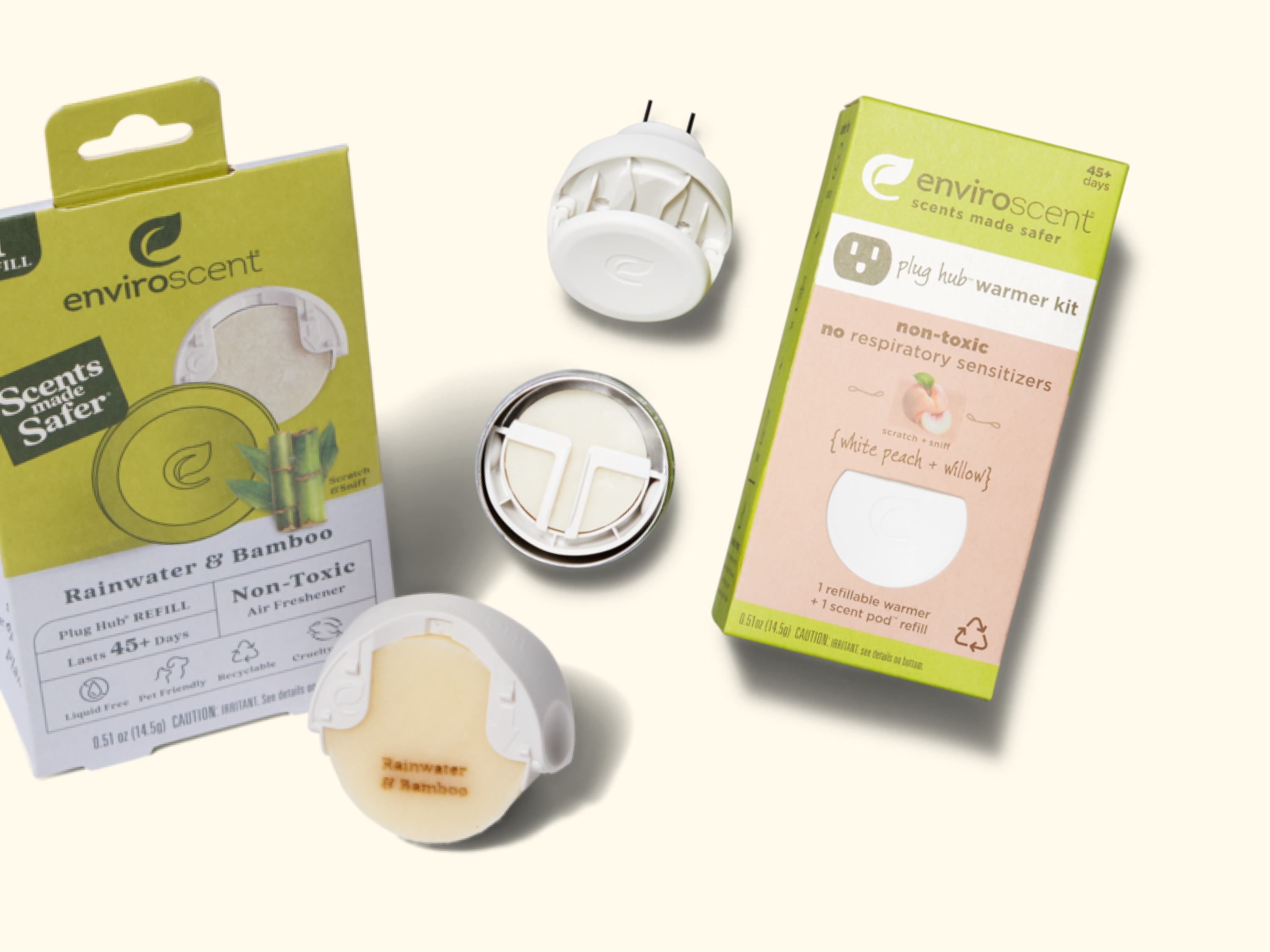 A flat lay of Enviroscent plug hub warmer kits in Rainwater & Bamboo scent, showing the packaging, plug-in device, and a scented refill disk on a light background.