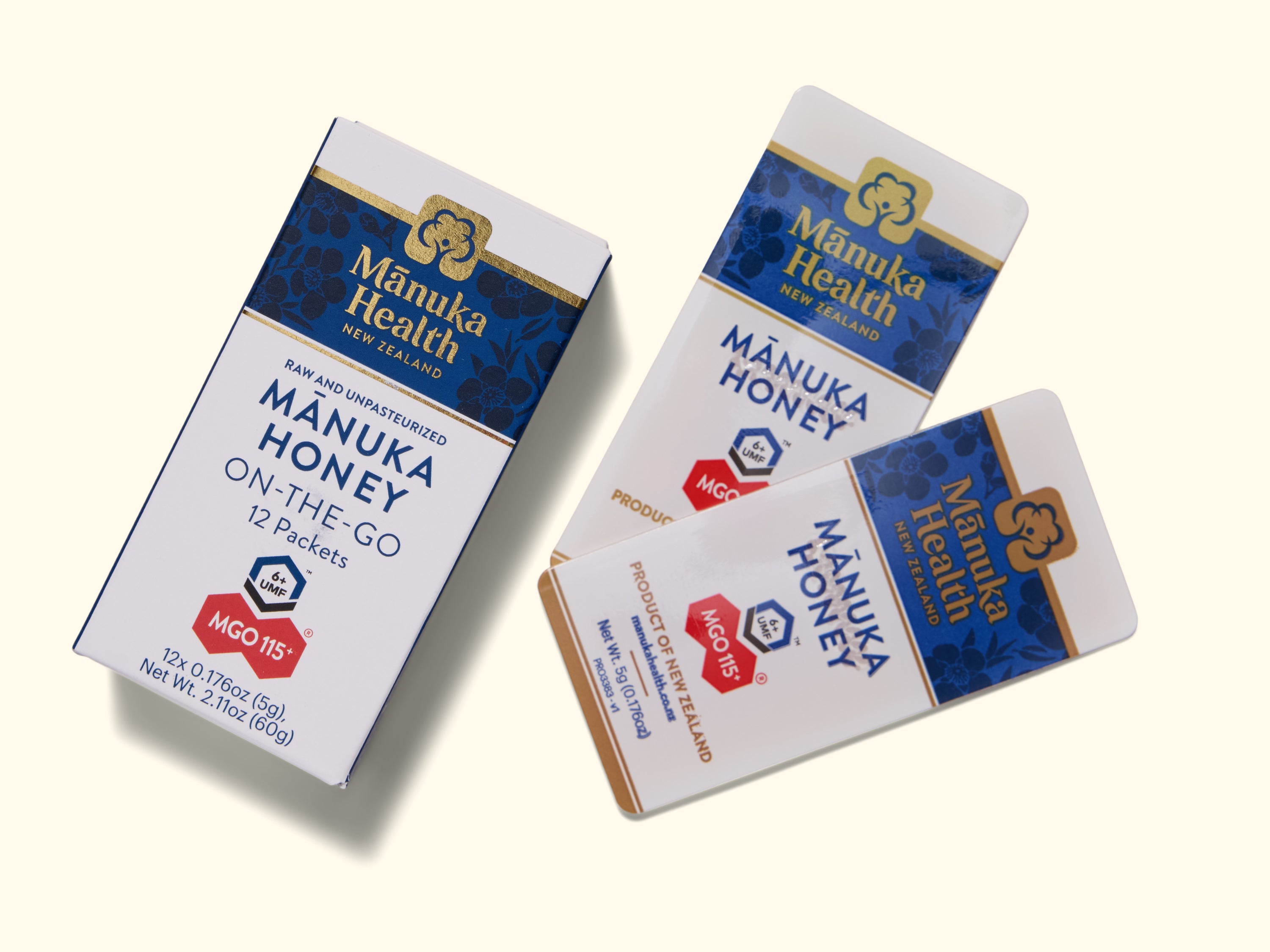 Three boxes of Manuka Health New Zealand Manuka Honey On-The-Go packets, featuring blue and gold packaging with red MGO markers, are displayed on a light background. Two boxes are open, revealing the product inside.