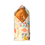 A loaf of sourdough bread is wrapped in a Bees Wrap Bread Wrap - Holiday, featuring vibrant birds, leaves, and flowers—a reusable, eco-friendly alternative to single-use waste—displayed against a white background.