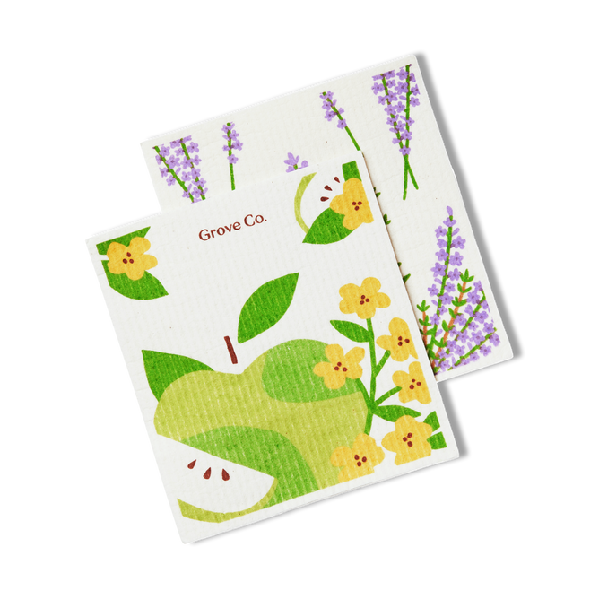 Two square Test Green Rewards cleaning cloths by Grove Collaborative: one with lavender sprigs, the other with a green apple, yellow flowers, and apple slices. Both feature Grove Collaborative branding.