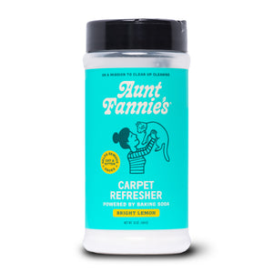 Aunt Fannies Carpet Refresher for Cats in Bright Lemon scent comes in a cylindrical container with a teal label featuring a woman holding a cat and highlights baking soda as a carpet and pet bed deodorizer.