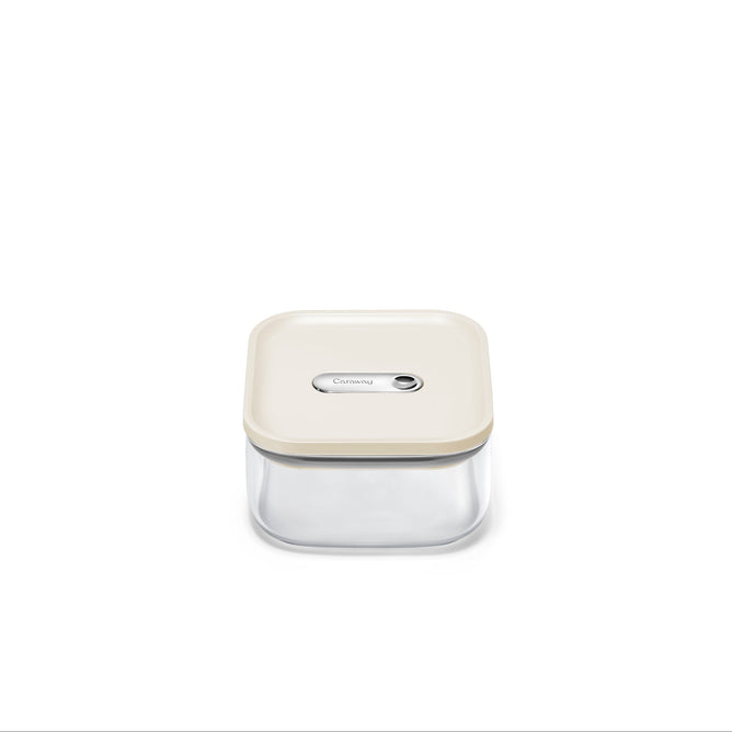 The Caraway Glass Small Container, 1 qt, is centered on a white background. It has a cream lid, is made from non-toxic glass, and features an airtight seal with a rectangular button for secure storage.