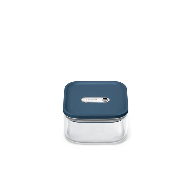 The Caraway Glass Small Container, 1 qt, features non-toxic glass with a dark blue button-seal lid. Its transparent square design is set against a plain white background.