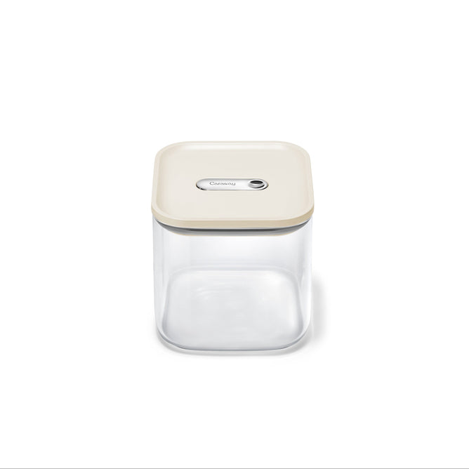 The Caraway Glass Medium Container (2.5 qt) is a clear, square, non-toxic food storage container with a beige airtight lid and central button—ideal for pantry organization. Shown empty against a white background.