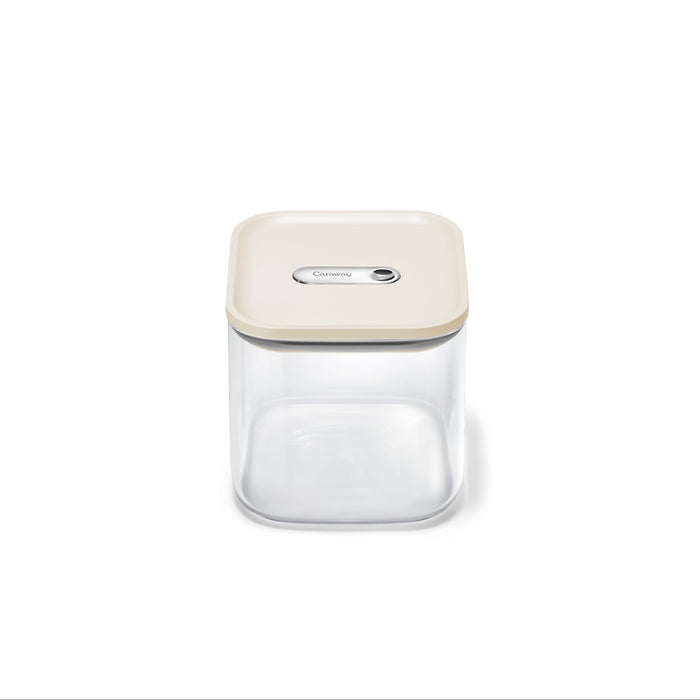 The Caraway Glass Medium Container (2.5 qt) is a clear, square, non-toxic food storage container with a beige airtight lid and central button—ideal for pantry organization. Shown empty against a white background.