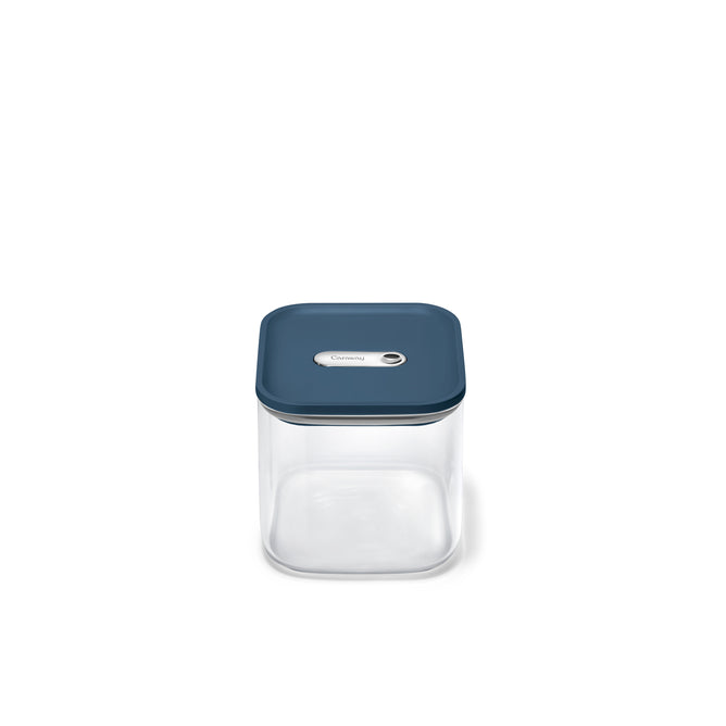 The Caraway Glass Medium Container, 2.5 qt, has a clear glass body with a teal blue lid and central silver button—ideal for non-toxic food storage and pantry organization, shown on a plain white background.