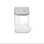 The Caraway Glass Large Container (4 qt) features a clear rectangular design with a gray airtight lid, including a central button, and is shown against a plain white background.