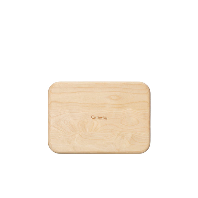 The Caraway Birch Wood Board is a small, rectangular FSC-certified birch cutting board with rounded edges and Caraway engraved in the center, shown on a white background.
