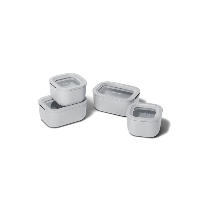 Four white, non-toxic Caraway Mini Food Storage Set with Organizer containers, each with a clear lid, are shown stacked and individually placed—providing an ideal kitchen organization solution on a white background.