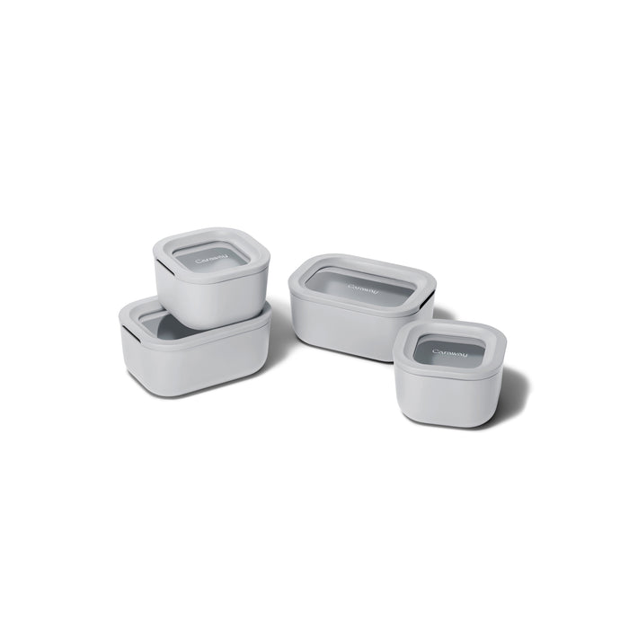 Four white, non-toxic Caraway Mini Food Storage Set with Organizer containers, each with a clear lid, are shown stacked and individually placed—providing an ideal kitchen organization solution on a white background.