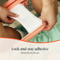 Close-up of hands placing Cora’s Peace of Mind Pad with lock-and-stay adhesive onto underwear. The text at the bottom reads: “Lock-and-stay adhesive. Once it’s on, it’s on.”.