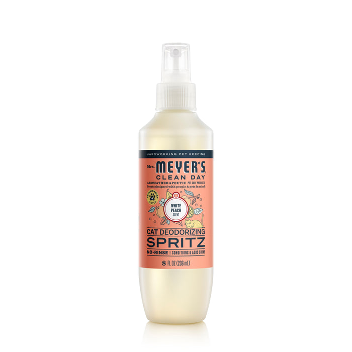 A bottle of Mrs. Meyer’s Clean Day Cat Deodorizing Spritz in White Peach scent, featuring a spray nozzle and orange label with product details and pet care information.