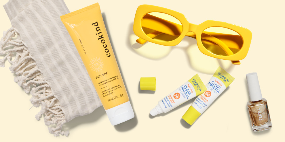 Sunscreen tube, sunglasses, and nail polish on a light background