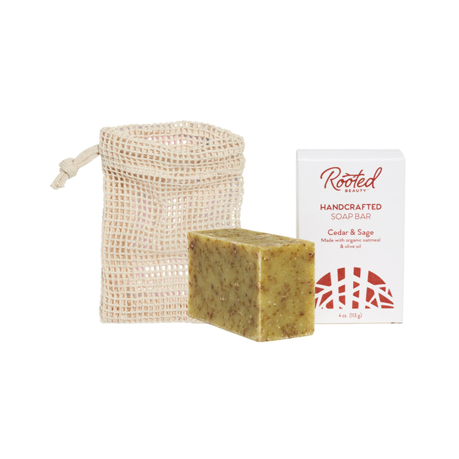 The Grove Collaborative Bar Soap + Saver Bag Duo is displayed on a white background, featuring a mesh pouch, a rectangular bar of soap, and a white box labeled Rooted Beauty Handcrafted Soap Bar, Cedar & Sage.