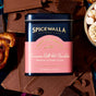 A tin of Spicewalla Deluxe Hot Chocolate - Cinnamon Roll is surrounded by chocolate bars, cinnamon rolls, chocolate chips, and a bowl of marshmallows.