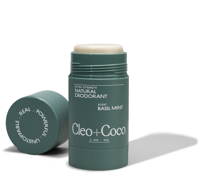 A green tube of Cleo & Coco Extra Strength Deodorant with activated charcoal in Basil Mint stands upright, cap off and beside it. The partially raised stick highlights its 24-hour protection.