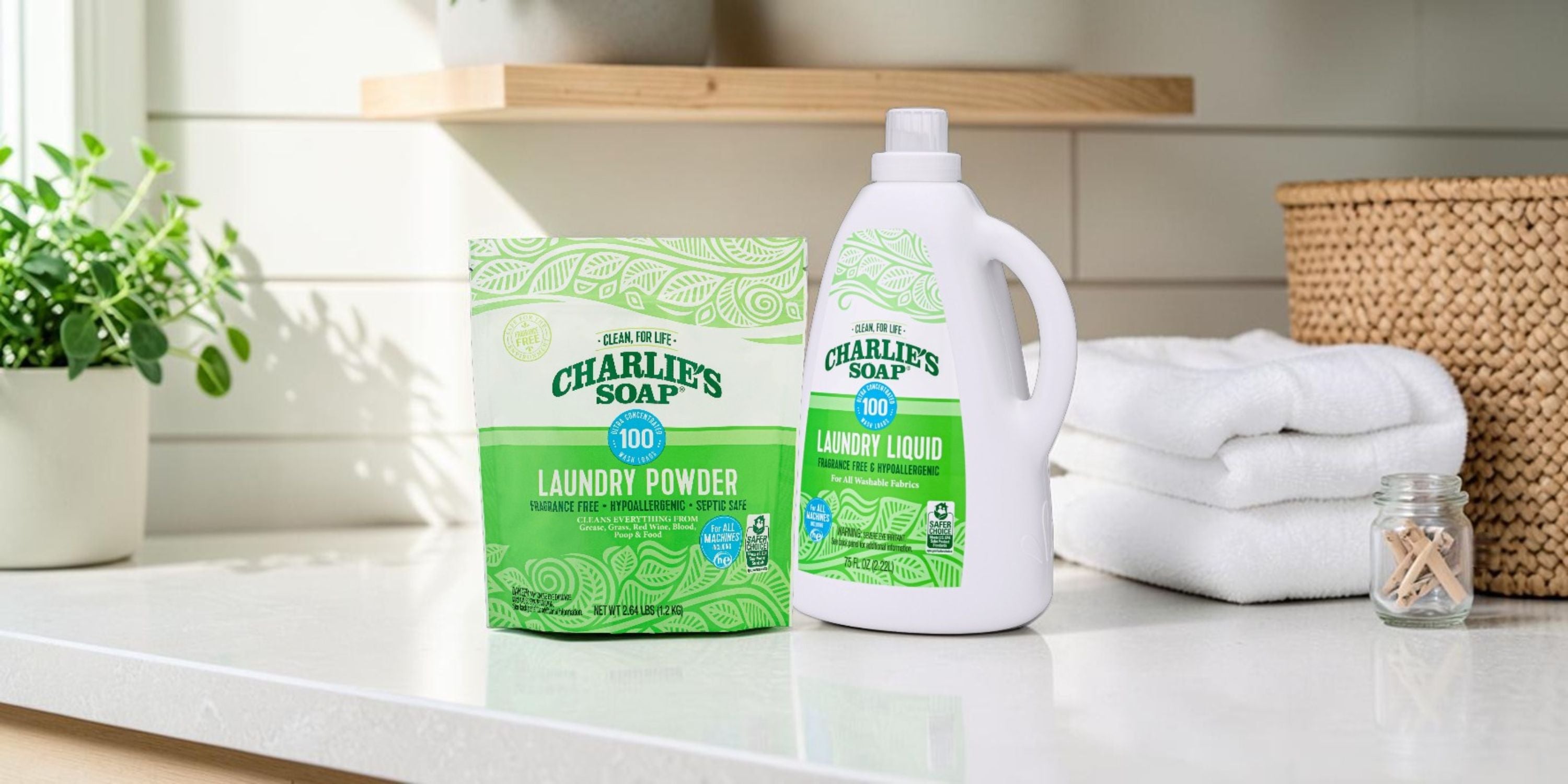 Charlie's Soap laundry powder and liquid on a kitchen counter with towels and a plant.