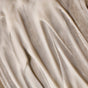 Close-up of Phil's Conditioner - Strengthening + Thickening, a creamy white formula for thinning hair, smoothly spread on a textured surface with soft ridges and glossy highlights that suggest healthy scalp care.