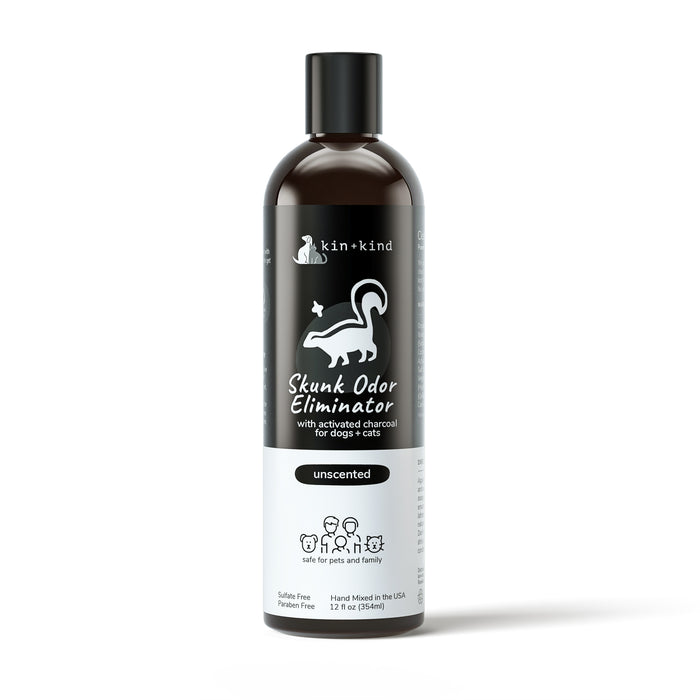 A black 12 oz kin+kind Skunk Odor Eliminator Shampoo bottle, labeled for dogs and cats with a white skunk graphic. It features unscented, sulfate-free activated charcoal shampoo thats safe for pets and families.