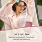 A woman in sunglasses and a pink hoodie lounges outdoors, holding a patterned pantyliner wrapper above her head. A box of Cora Got-You-Covered Pantyliners – Light Absorbency is shown. Text reads: Let it (air) flow. Maximize coolness with a breathable topsheet and backsheet—and enjoy all-day comfort with our hypoallergenic liner from Cora.